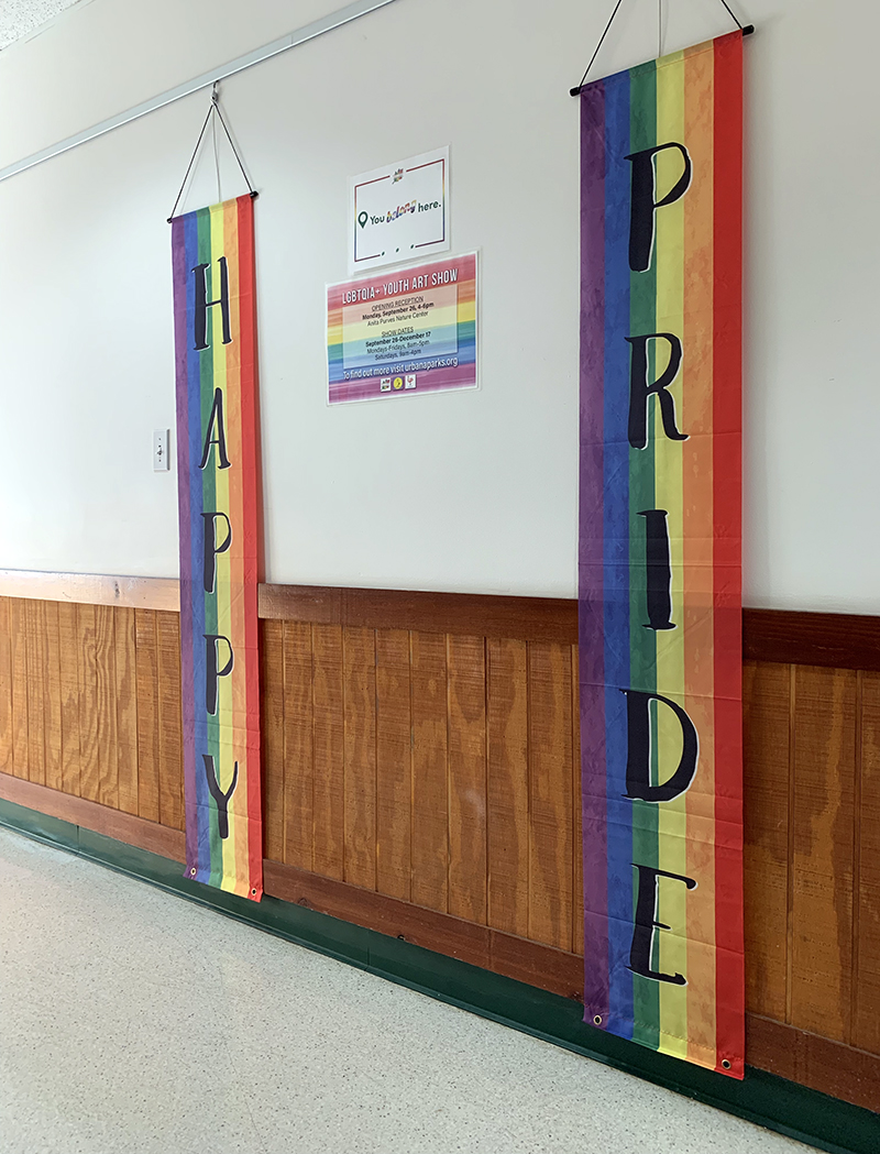 Two long vertical Pride flags with the words 