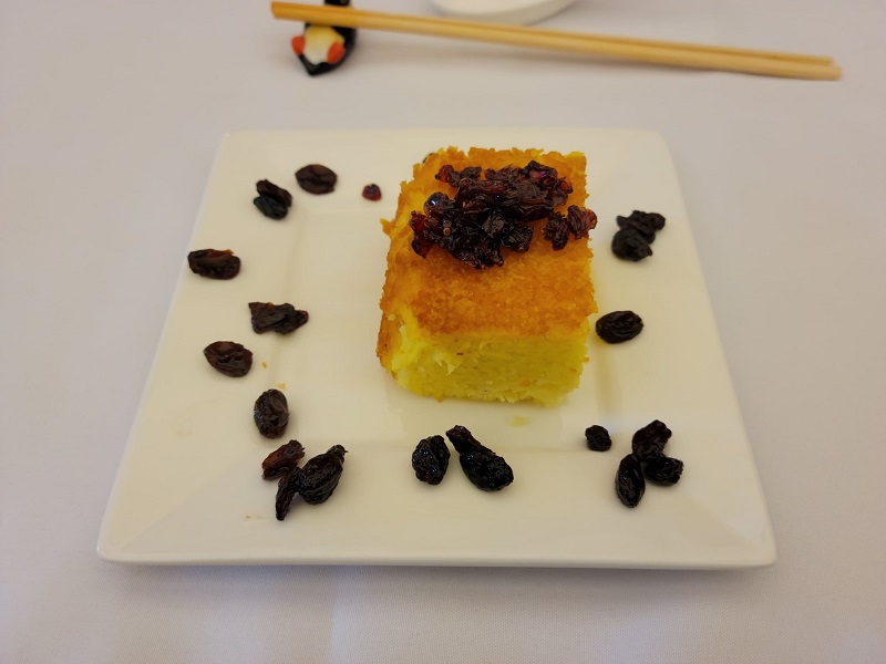 Tahchin with barberries on top of the cake and raisins scattered all around the cake slice. Photo by Matthew Macomber.