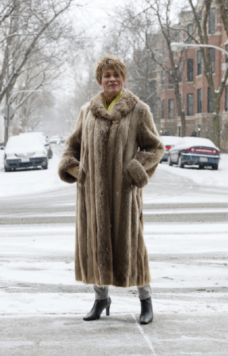 A photo of the late Mama Gloria in a fur coat standing on a snow-covered city street.