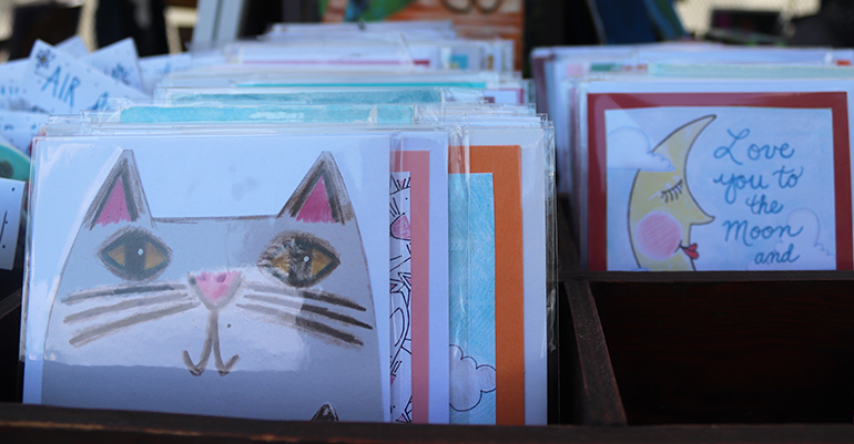 A selection of illustration prints in boxes. The one up front is a close-up of a cat. 