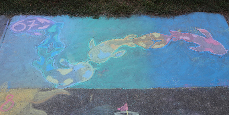 Close-up photo of a sidewalk chalk drawing of fish and sea creatures.