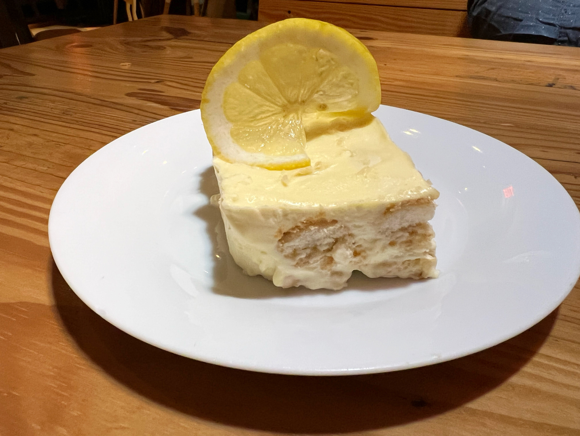 On a white plate, there is a slice of tiramisu topped with a lemon. Photo by Alyssa Buckley.