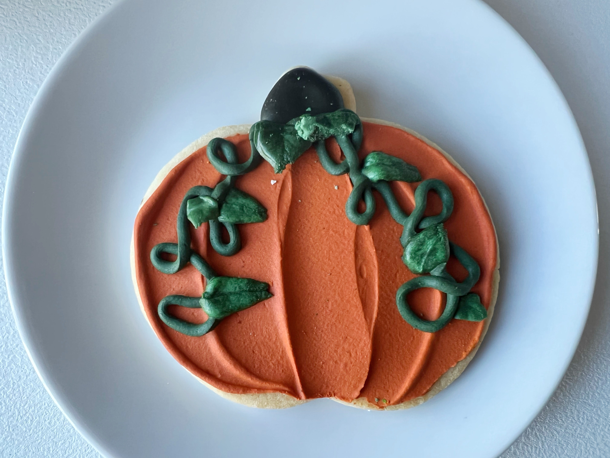 On a white circular plate, there is a pumpkin cookie from Central Illinois Bakehouse. Photo by Alyssa Buckley.