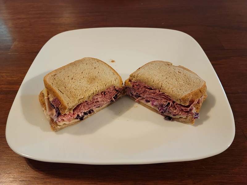A corned beef and Swiss cheese sandwich cut in half on a square plate. Photo by Matthew Macomber.