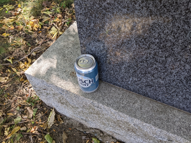 An unopened can of Busch Light sits on the base of a headstone. Photo by Tom Ackerman.