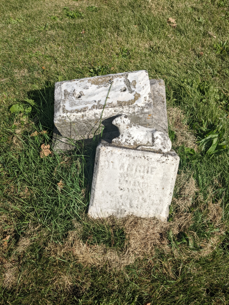 Two very old headstones, partially sunken. One appears to have a figure of a lamb on top. Photo by Tom Ackerman.