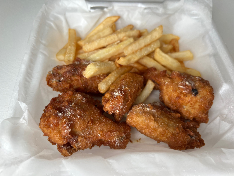 In a parchment paper lined container, there are five crisy wings with a side of fries. Photo by Alyssa Buckley.