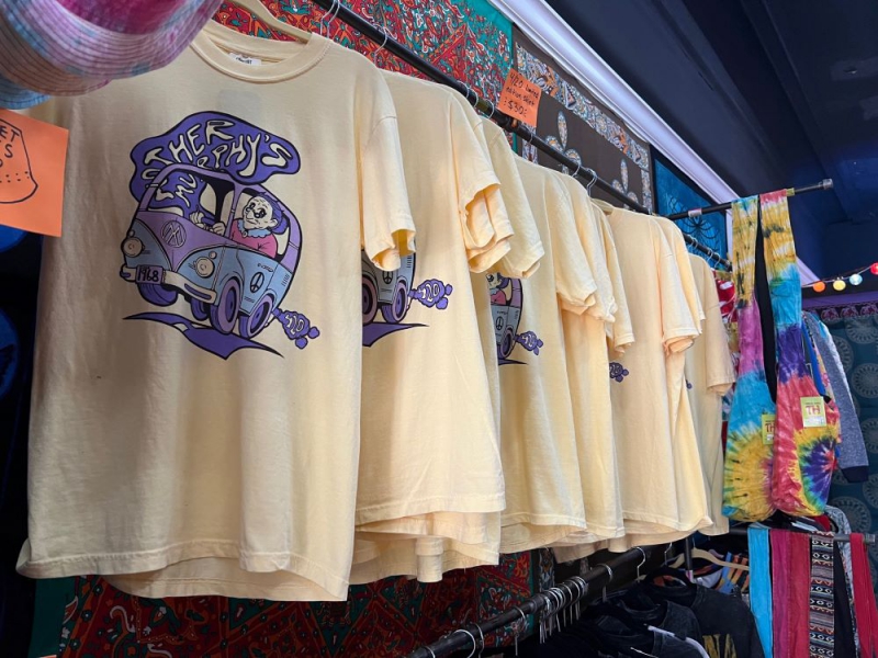 A row of pale yellow t-shirts with a blue swirly logo that says Mother Murphy's are hanging on a rack. Photo by Julie McClure.