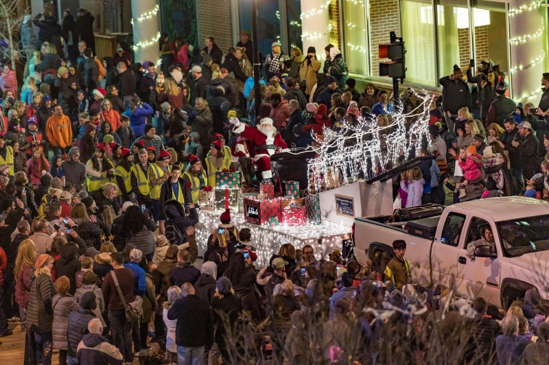 A lighted truck with someone dressed as Santa Claus is surrounded by a crowd of people. Photo from Champaign Center Partnership Facebook page.