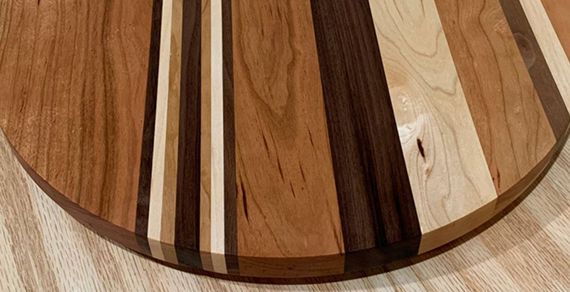 Cropped photo showing details of multi-wood striped round board by RAB Woodworking.