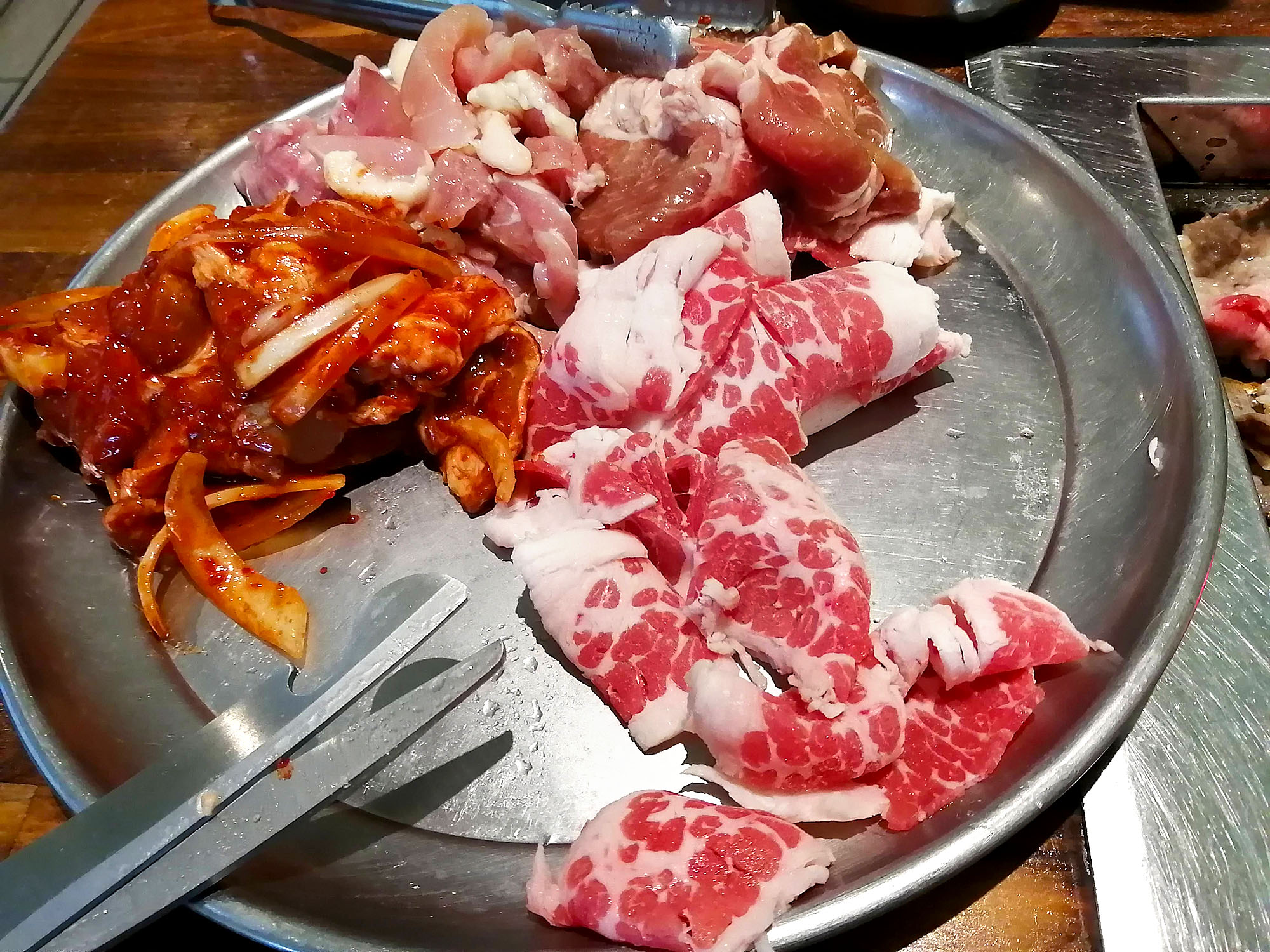  An image of a large platter with four different kinds of raw meat with a pair of large scissors visible. Photo by Paul Young.