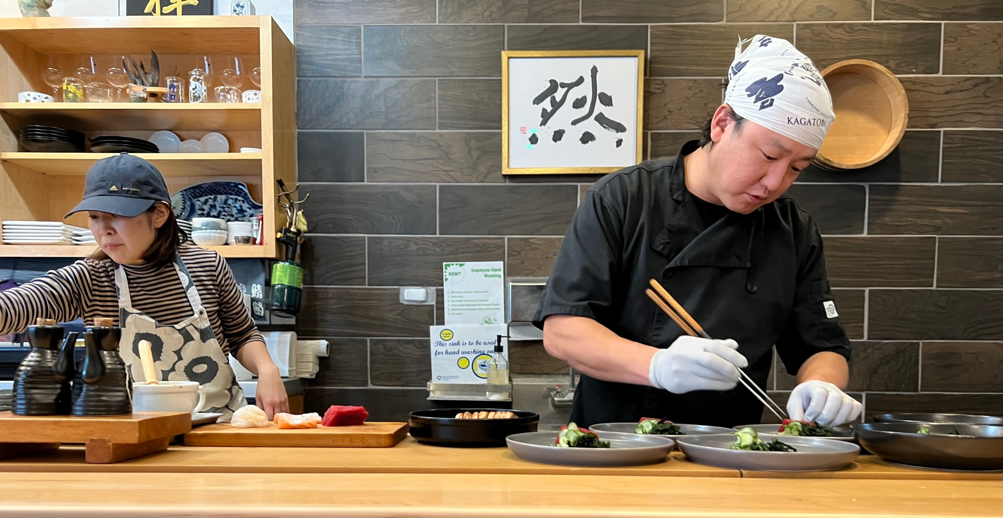 Chef Ken Ishibashi plates omakase at ISHI in Champaign. His wife Kaori assists on the left. Photo by Alyssa Buckley.