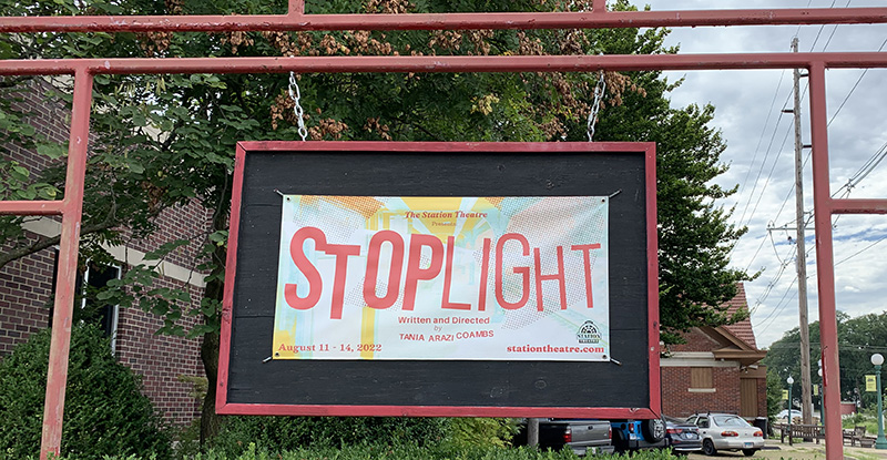 Photo of a horizontally oriented banner for the play Stoplight hanging outside of the Station Theatre in Urbana. Photo by Debra Domal.