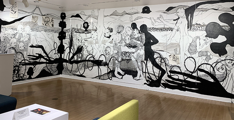 Wide shot photo of William Downs' two-wall temporary installation from In Blackest Shade, in Darkest Light at Giertz Gallery, created on canvas and paper, featuringnn black ad white figures staring, pointing, and recording on their phones.