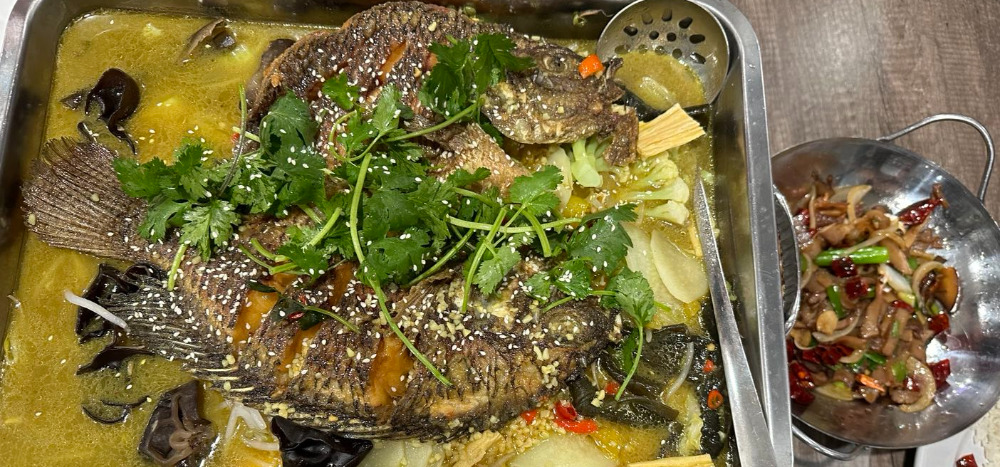 A cropped photo shows two grilled fish on vegetables at Szechuan Taste in Champaign, Illinois. Photo by Xiaohui Zhang.
