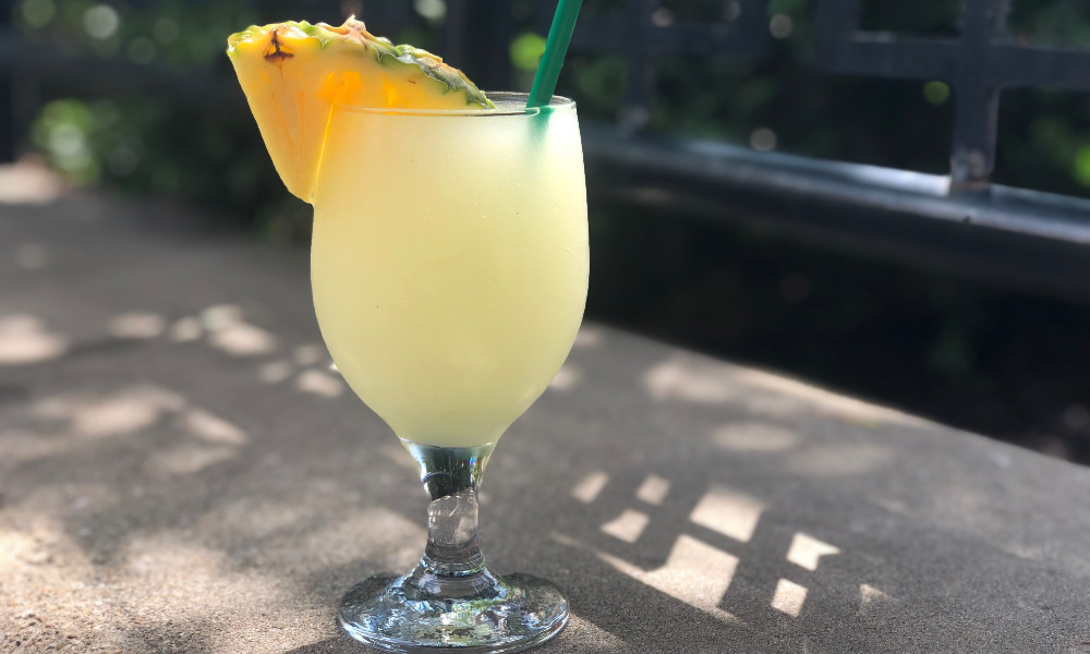 A pineapple margarita slush with a wedge of pineapple sits on a concrete ledge in Downtown Champaign outside of Esquire Lounge. Photo by Alyssa Buckley.