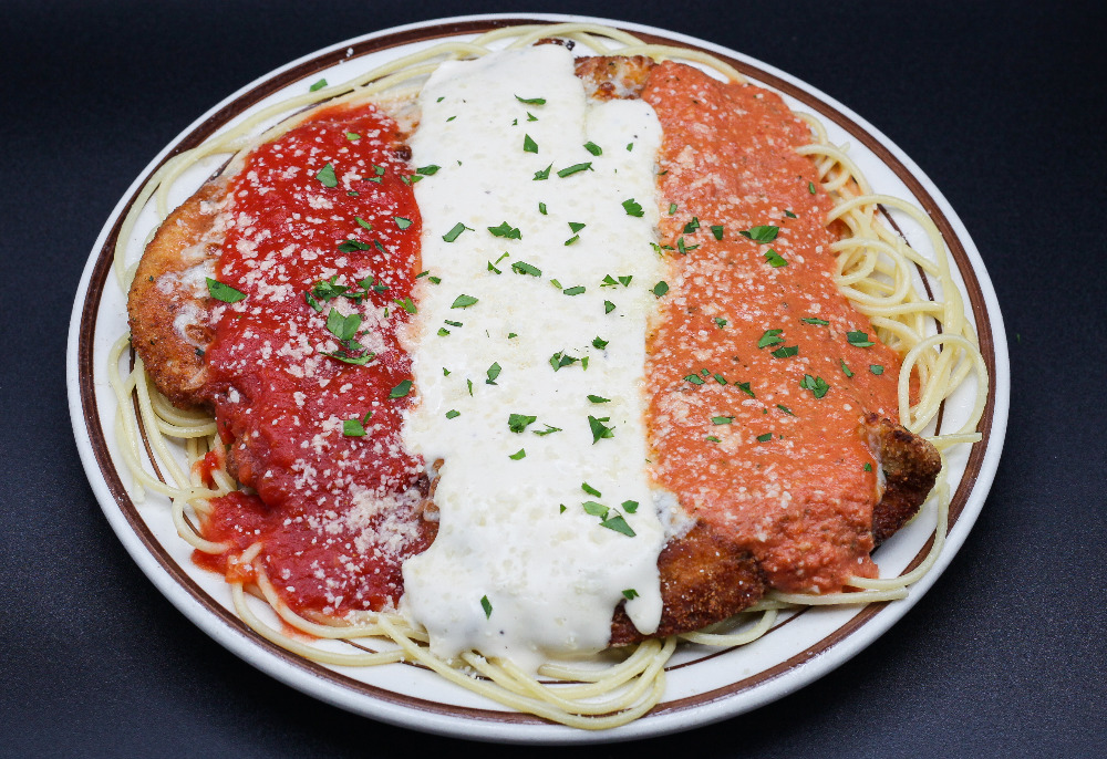 A plate of noodles with breaded chicken and three rows of different sauces by Watson's Shack and Rail in Champaign, Illinois. The dish is called Sauce Boss Chicken Parm as part of Restaurant Week 2023. Photo from Visit Champaign County website.