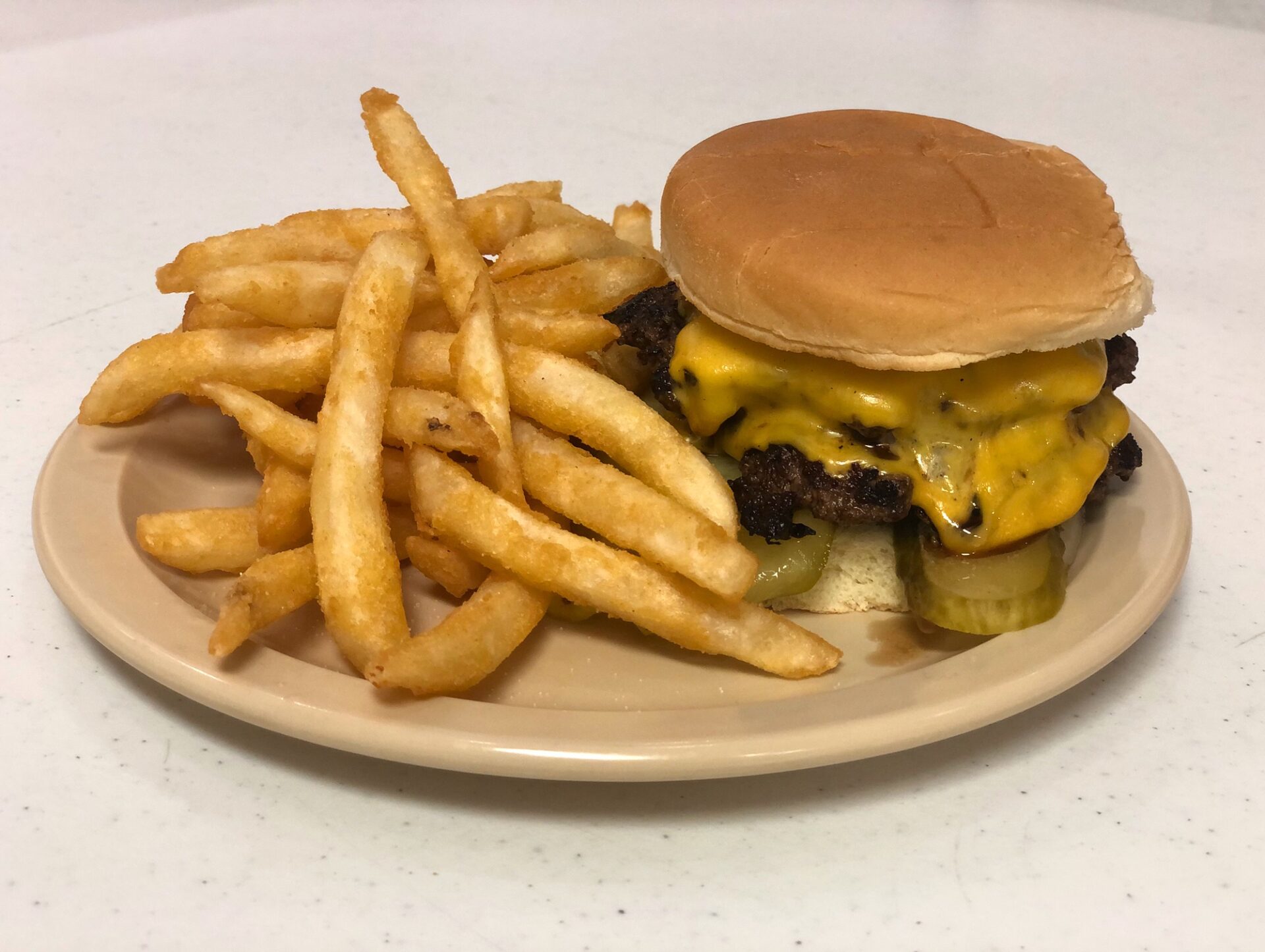 A cheeseburger on an oval plate with a side of fries at VFW #630's restaurant. Photo by Alyssa Buckley.
