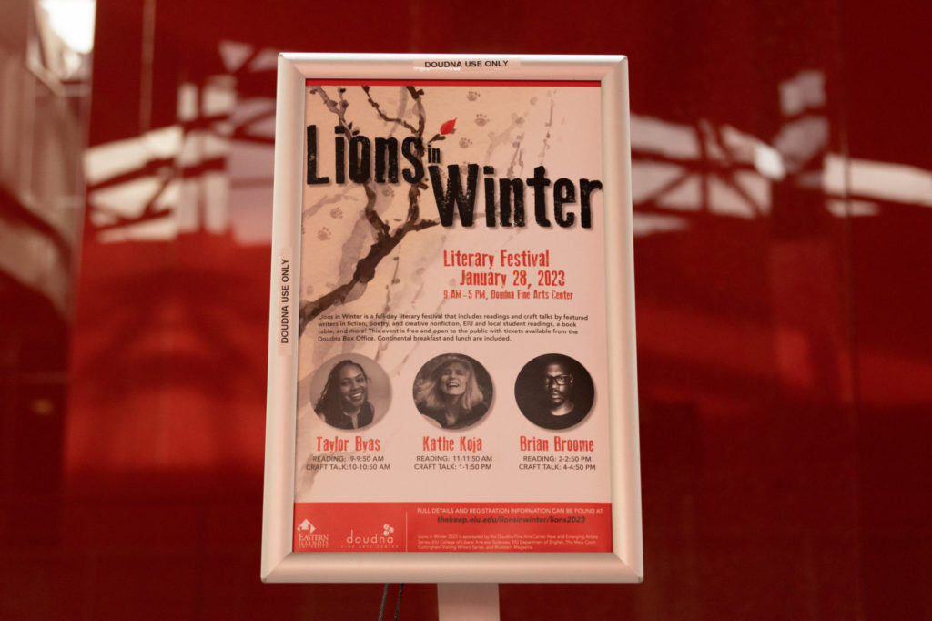 A sign for Eastern Illinois University's Lions in Winter festival is in a framed sign post. The wall behind the sign is red. The poster contains information about the day's festival and guests.