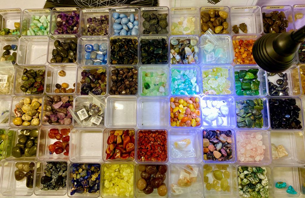 A grid of clear plastic cube shaped containers. Each has a different type of rock or crystal contained within it.