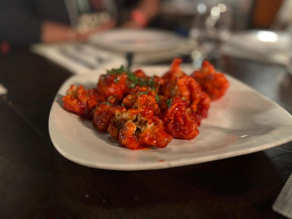 Lassoni gobi with a bright red sauce sit on a white plate at Himalayan Chimney. Photo by Rashmi Tenneti.