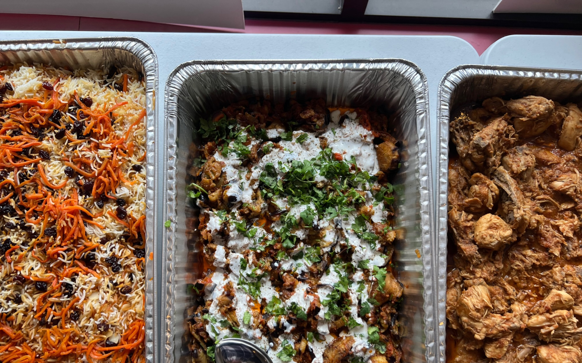 An overhead photo of three dishes in catering pans at Afghan Cuisine in Urbana. Photo by Alyssa Buckley.