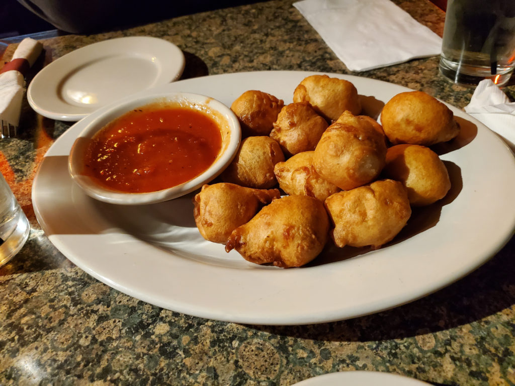 A white plate of Seven Saint's cheese curds with a small bowl of marinara sauce on the side. Photo by Carl Busch.