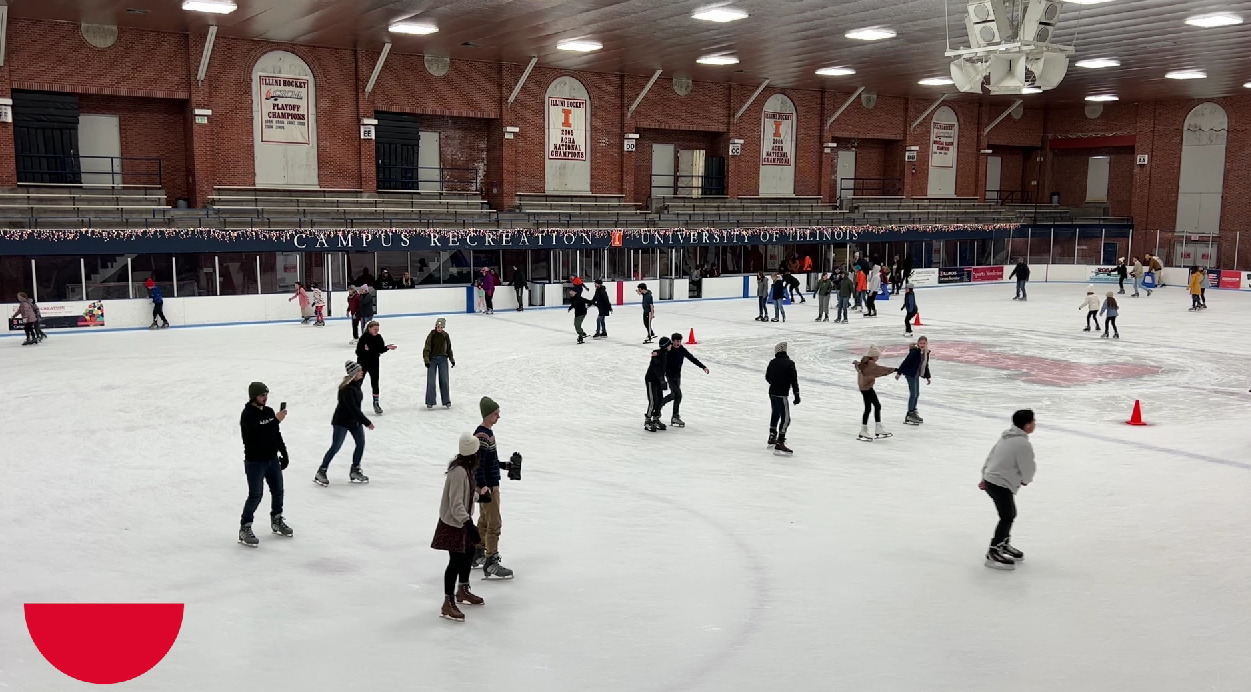 Wide view of an ice skating rink, with people on skates scattered throughout.
