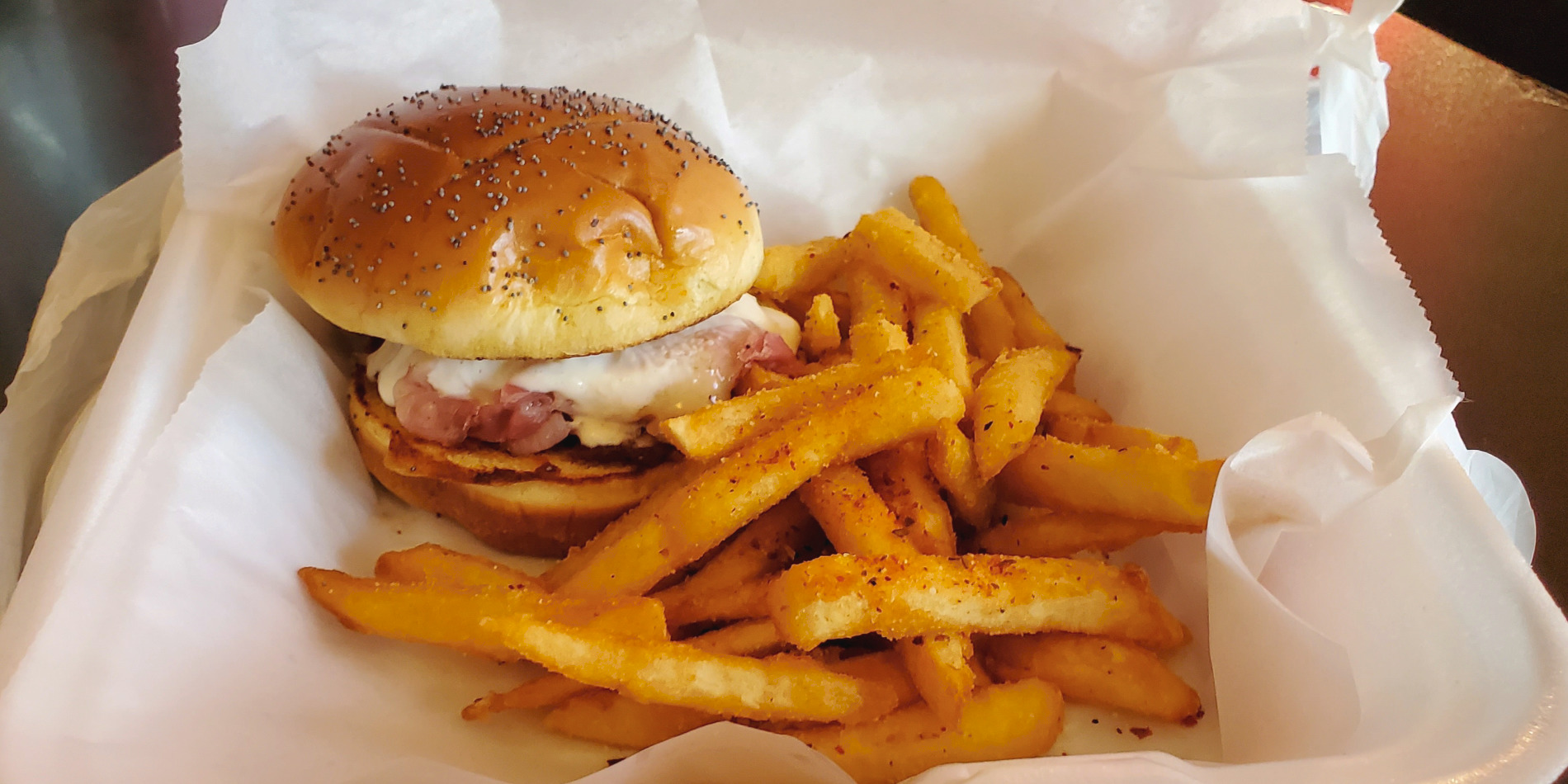 Pond Street's hot ham and cheese sandwich with seasoned fries in a parchment paper lined styrofoam container. Photo by Carl Busch.