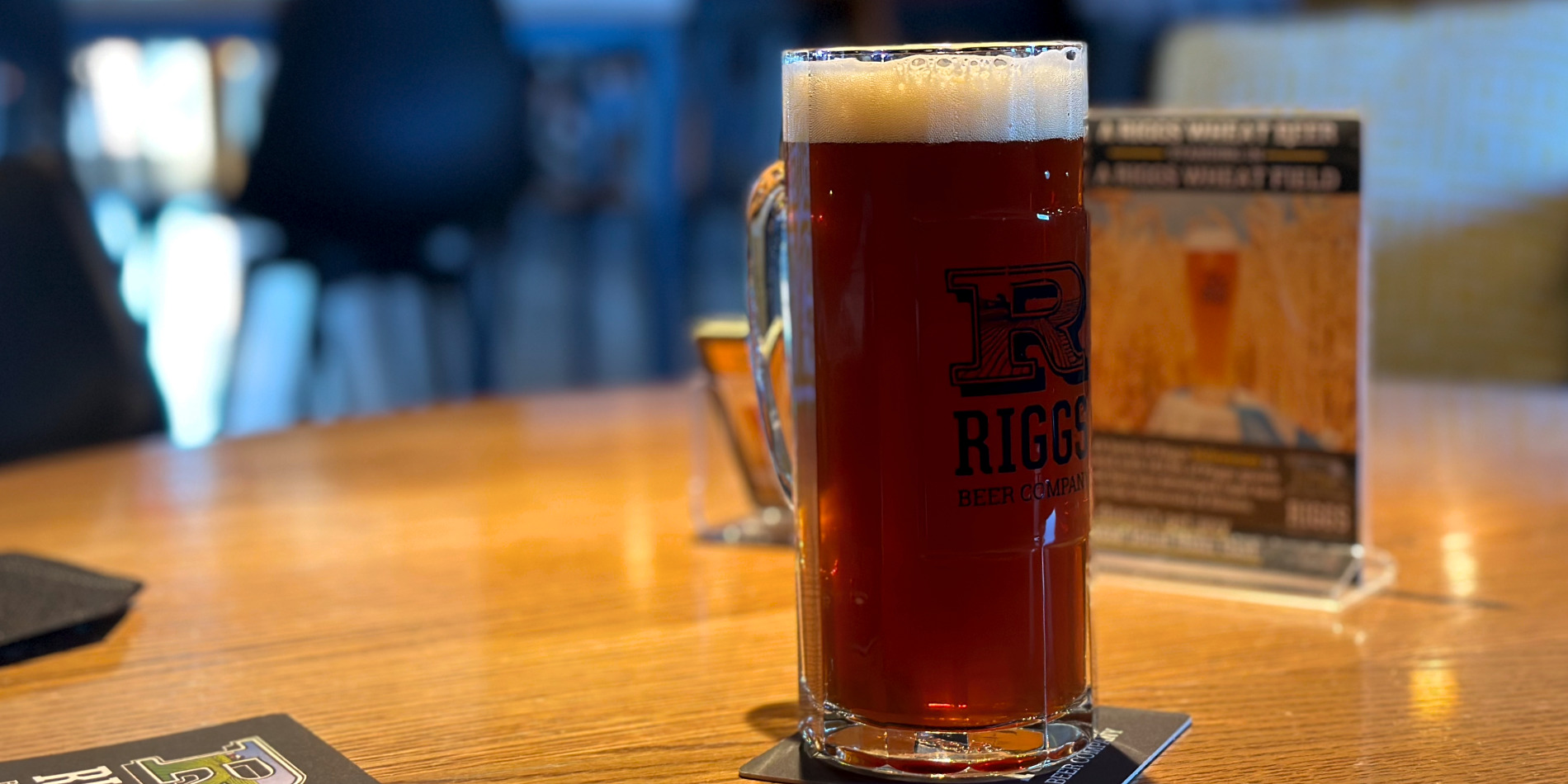 On a warm wooden counter inside Riggs Brewing Company in Urbana, Illinois, there is a red lager in a glass. Photo by Jake Williams.