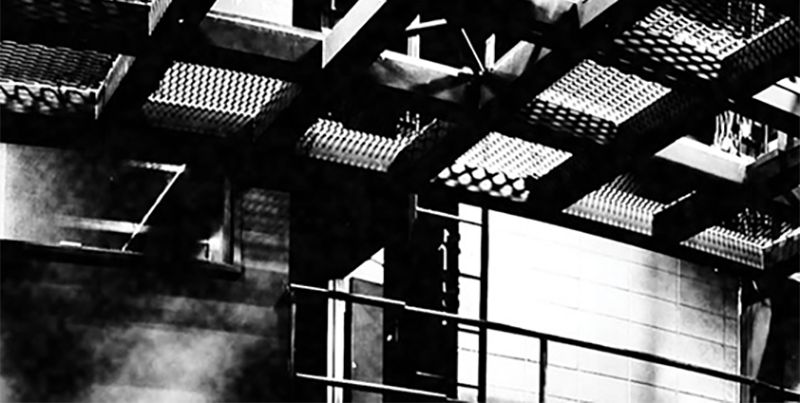 Cropped black and white photo of the top of a theatre space with a catwalk and ladders.
