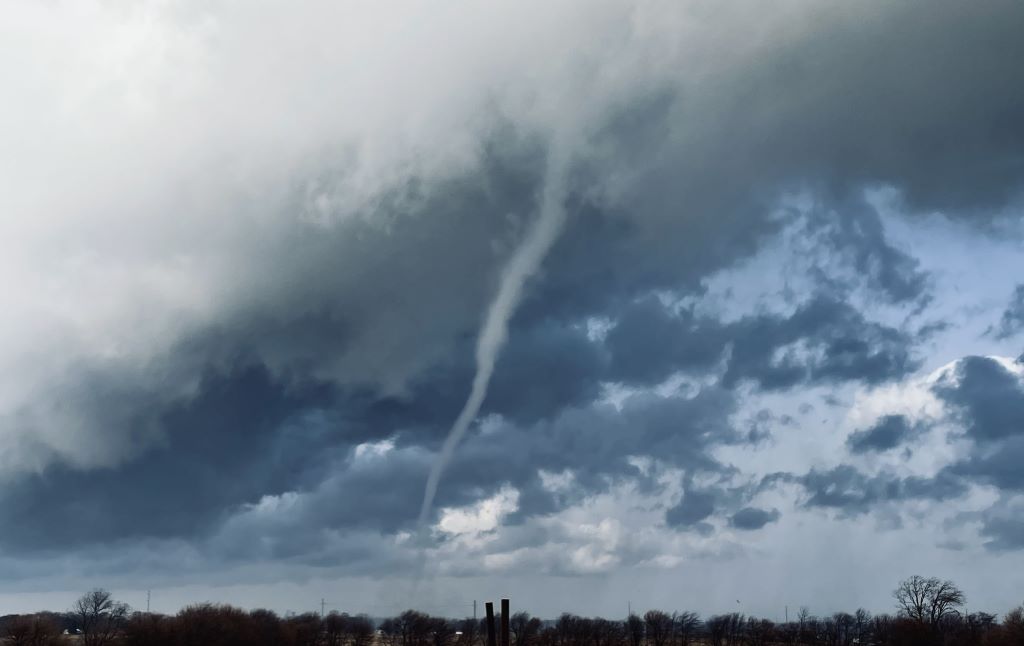 A thin funnel cloud is stretching down from a large whitish gray cloud.