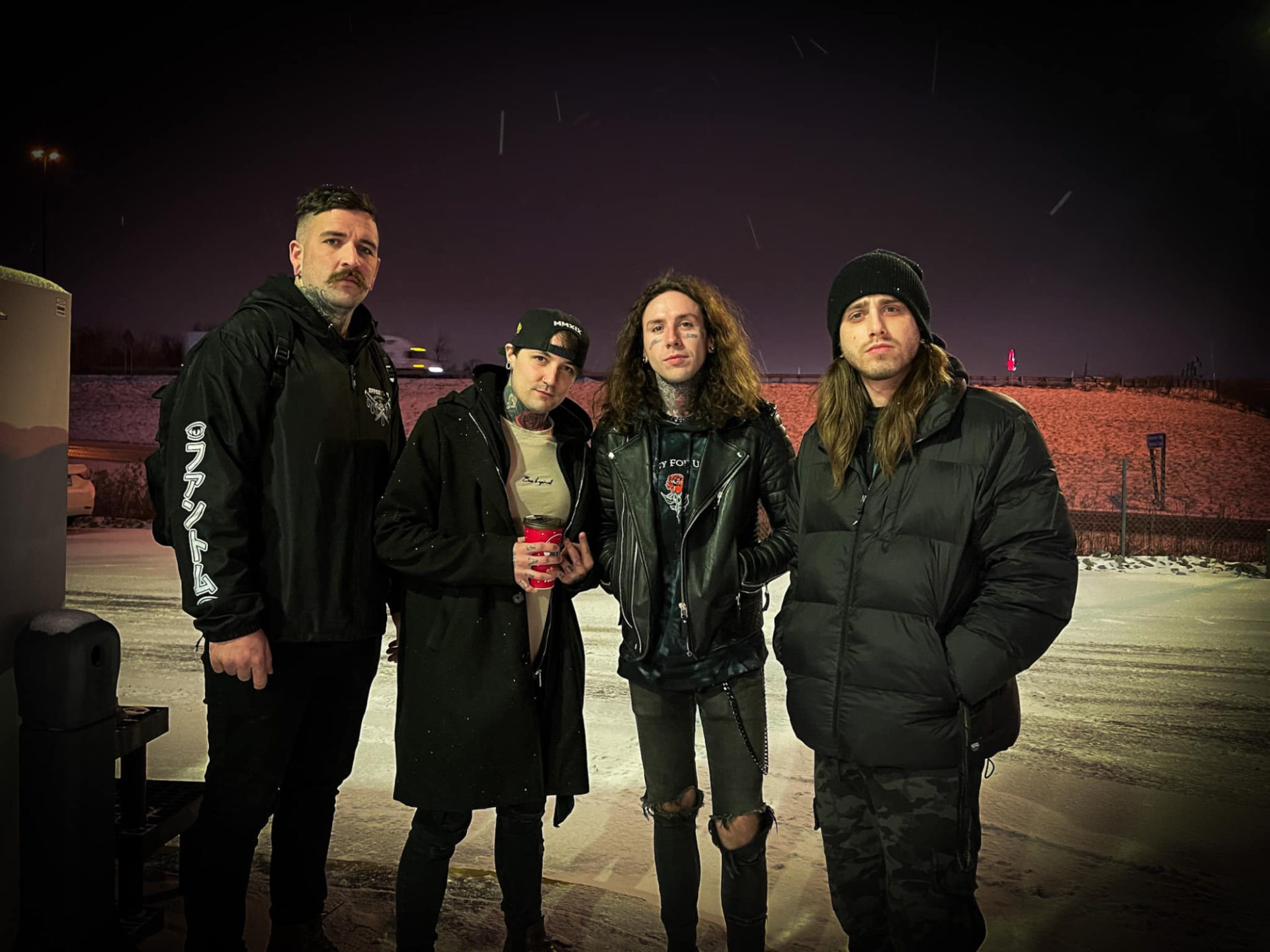 Band Until I Wake, four white men in dark, goth-metal-like clothing standing in a parking lot. It looks cold, and they are all wearing black jackets.