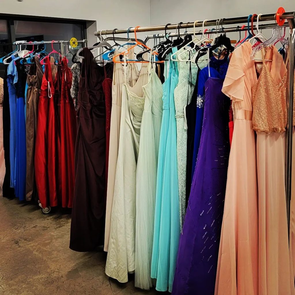 Many different colored formal dressed hang on metal racks