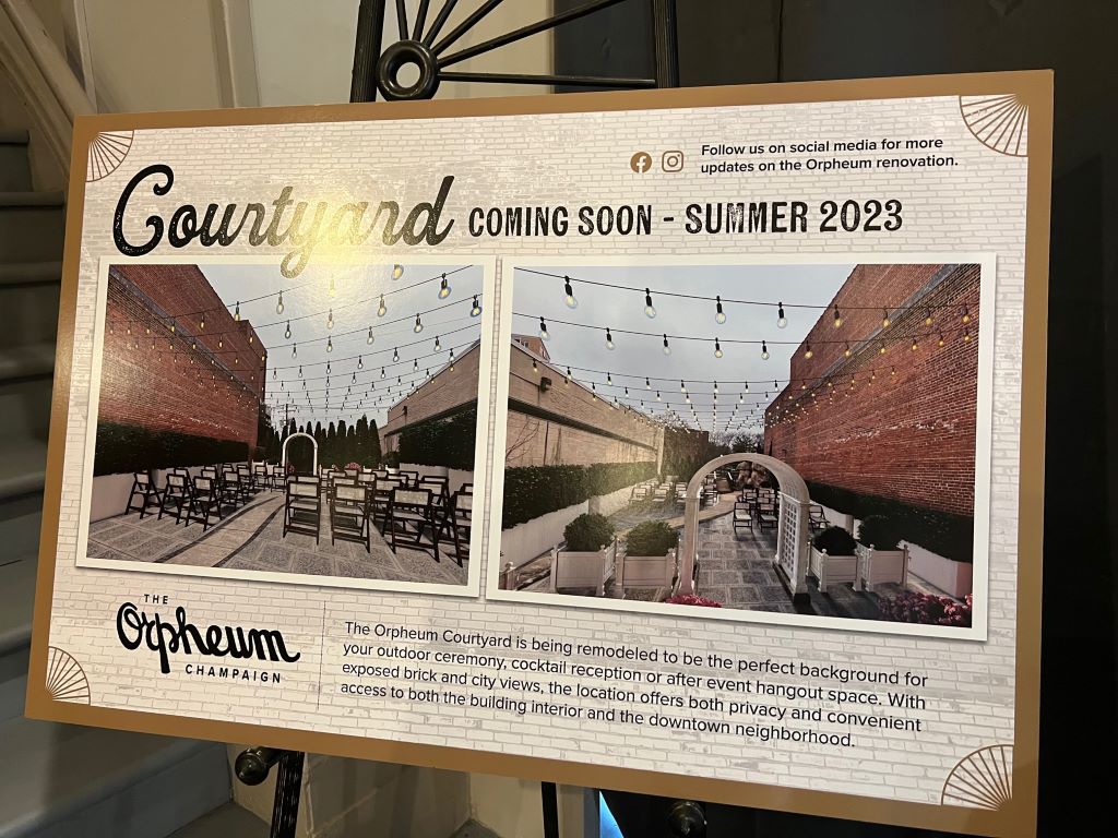 A large sign with schematic renderings of an outdoor patio. 