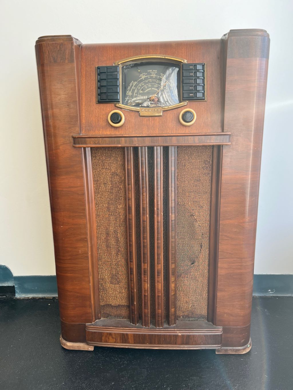 An old stand-up wooden radio with black and gold dials.
