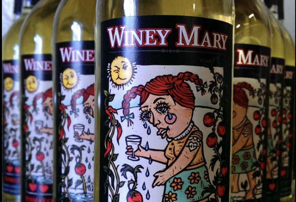 Closely cropped image of many bottles of Sleepy Creek Vineyards' Winey Mary tomato and jalapeño wine. The label is a drawing of a white woman with big eyes and red hair crying big, fat, blue tears among tomato plants. 