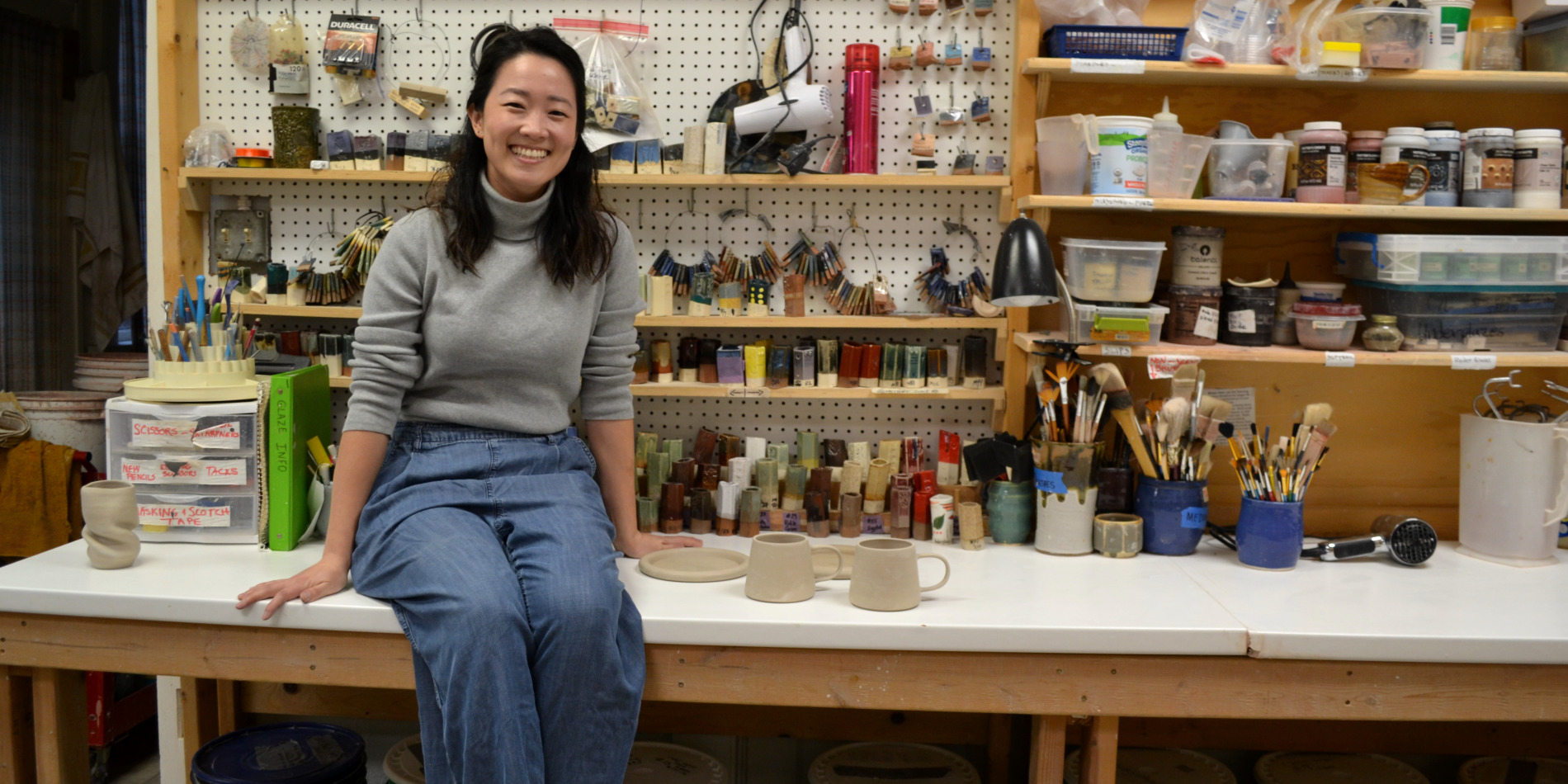Artist Hye-Min Kim sits on a white counter in the pottery studio. Photo by Alyssa Buckley.