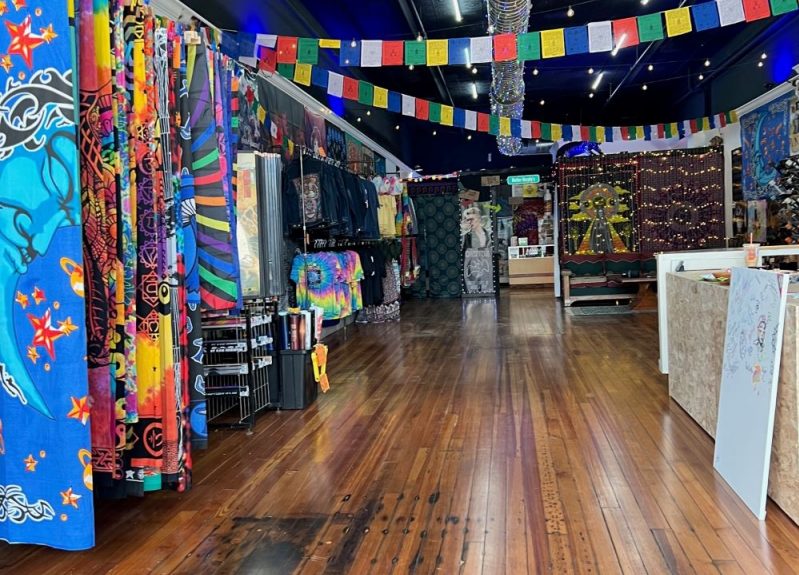 The interior of a store with wood floors. There are colorful flags strung across the ceiling, tapestries hanging along the side.