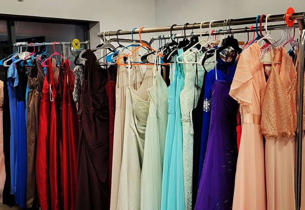 A rack with long dresses of different colors hanging side by side.