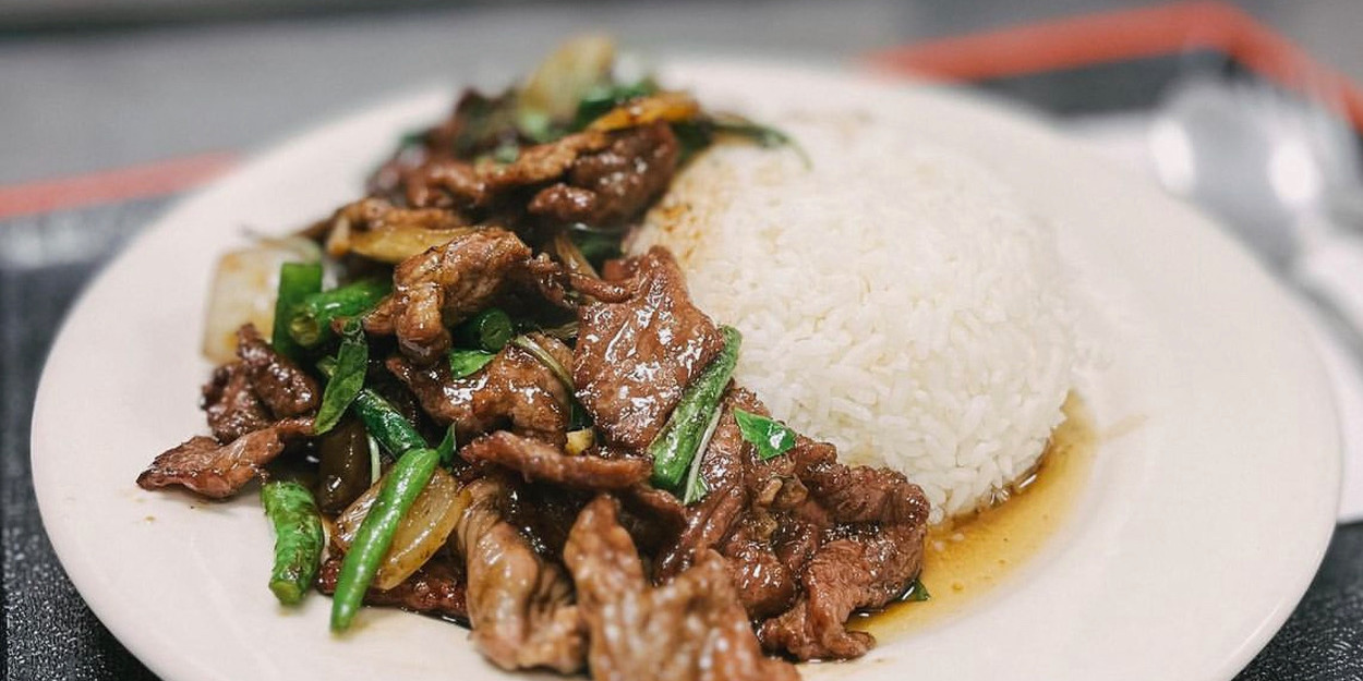 On a white plate, there is beef with wilted basil beside a heap of white rice from Thai Fusion. Photo by Thai Fusion on Instagram.