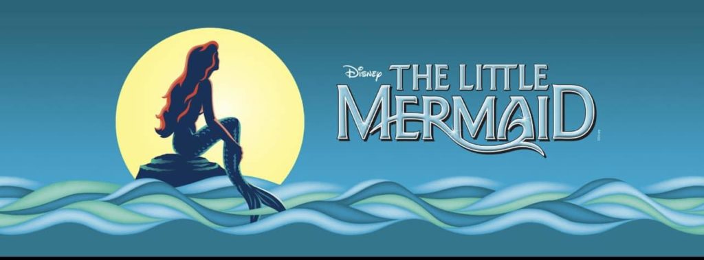 Graphic of The Little Mermaid. The Disney artwork is used. Ariel, the mermaid, is sitting on a rock that protrudes from the sea. She has red hair. The moon frames her and is bright and yellow. The waves on the ocean are blue and green. 