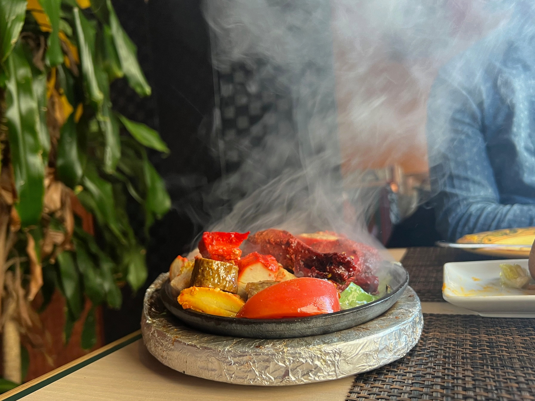 A sizzling skillet of Indian meats has a plume of smoke and brightly colored meats. Photo by Alyssa Buckley.