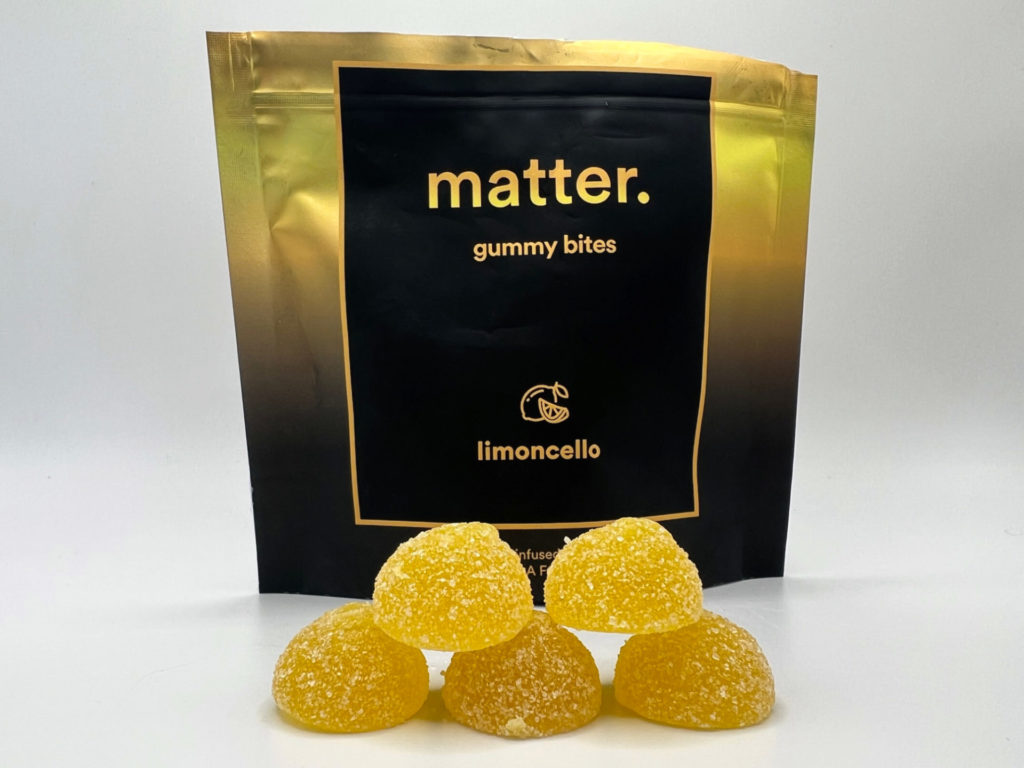 Five yellow gummies are stacked in a pyramid formation in front of a black and yellow bag of matter limoncello gummies for 4/20 in Champaign-Urbana. Photo by Alyssa Buckley.