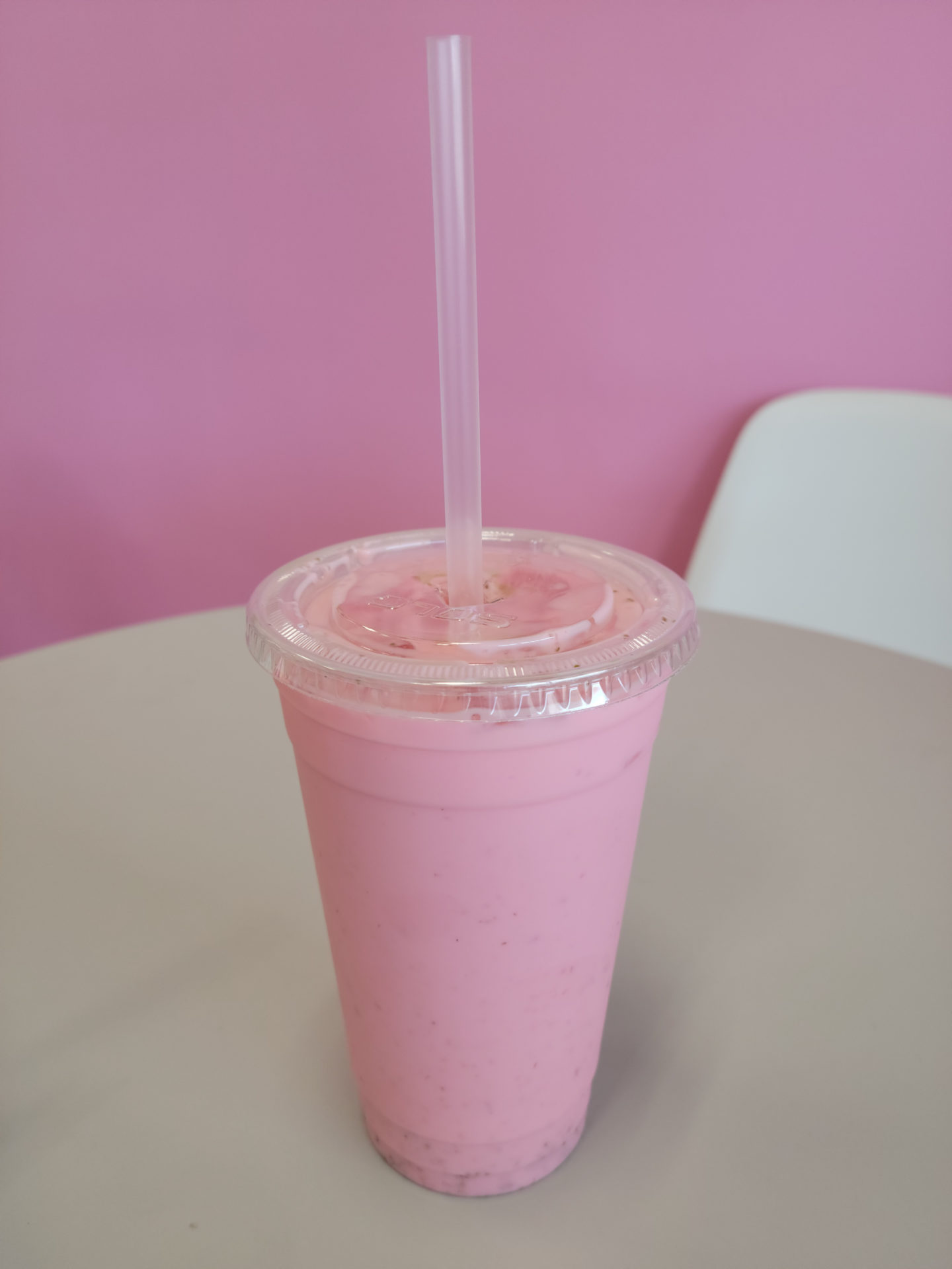 A medium plastic up of strawberry drink with a plastic straw. Photo by Matthew Macomber.