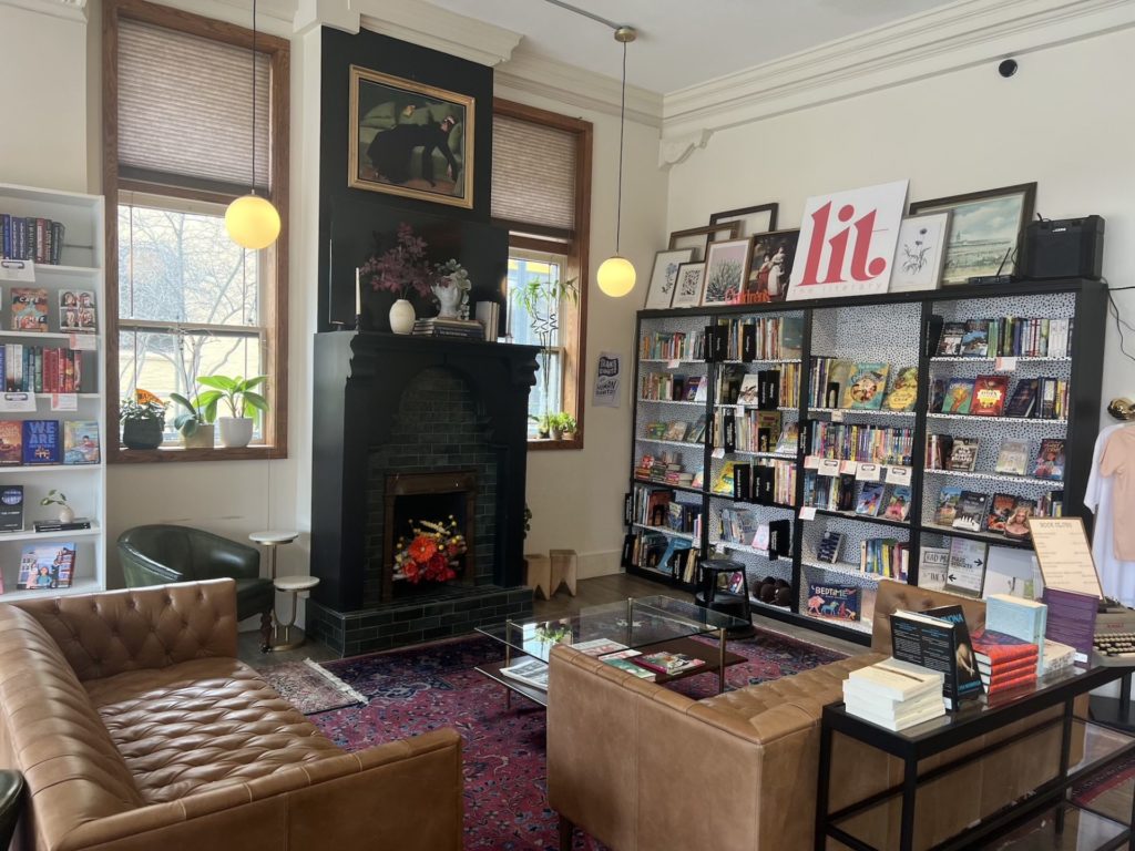 The inside of the Literary bookstore. Leather couches are positioned in front of a black fireplace and surrounded by bookshelves.