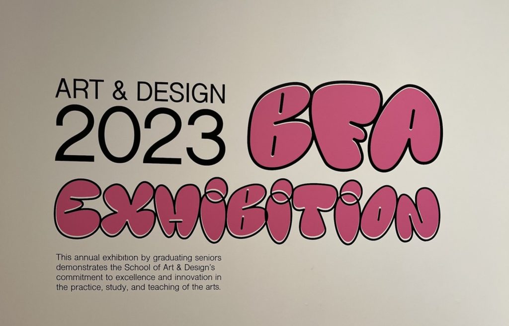 The sign on the wall of Krannert Art Museum: Black font reads "Art & Design 2023" ; large pink bubble letters read "BFA exhibition"