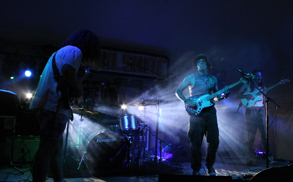 A dark stage with 3 visible members of the band Kangaroo Court