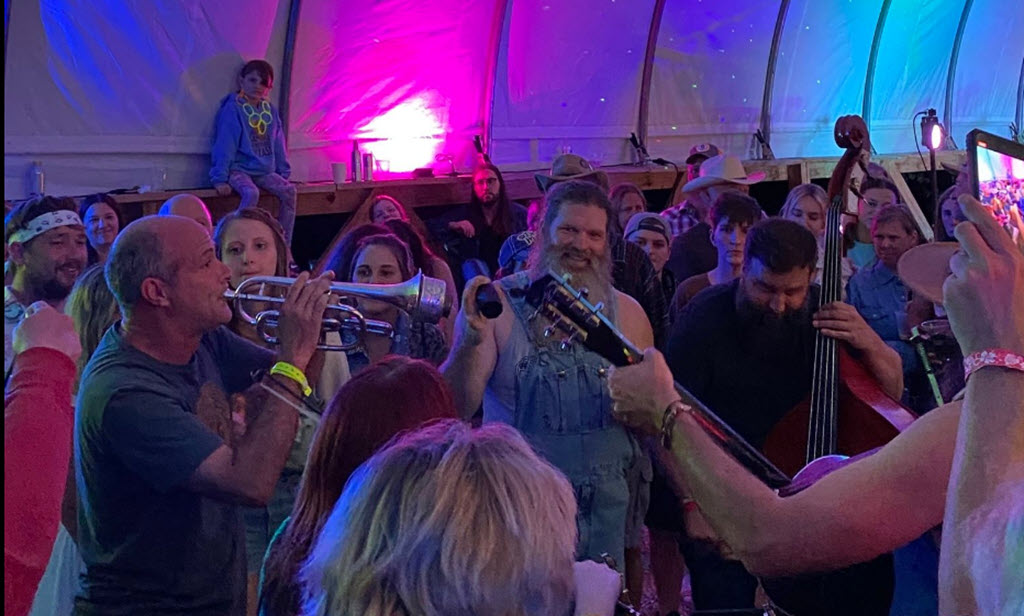 A band amongst the crowd playing under a tent at the Moccasin Creek Festival.