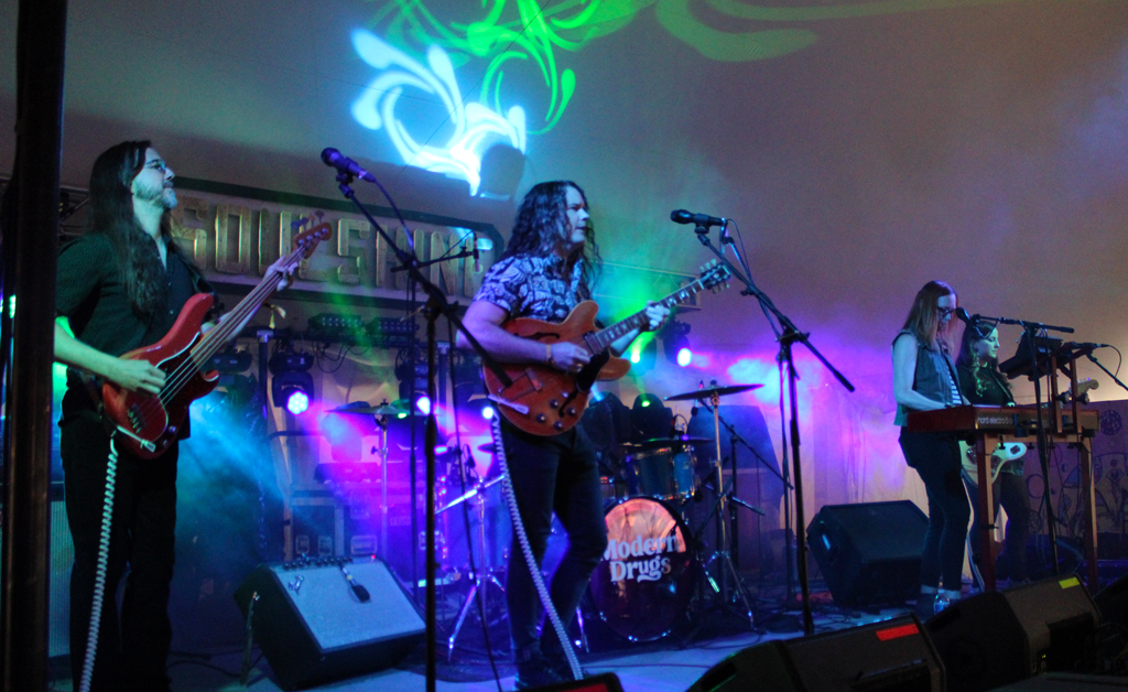 4 visible members of the band Modern Drugs performing onstage